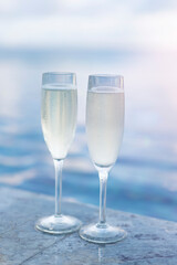 Two glasses of champagne on the side of the infinity pool against the backdrop of a sunset in the Maldives