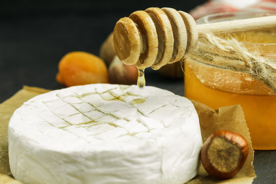 A drop of honey drips onto camembert cheese