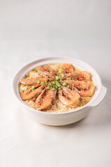 poached fried jasmine rice with giant tiger sea prawn and green bean vegetable in yellow golden chicken stock cheesy sauce in claypot on wood table asian chinese halal food seafood menu for restaurant
