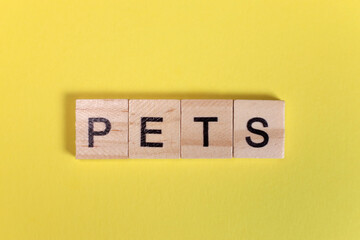 Pets word from wooden letters on yellow background