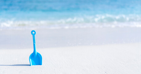 Children's toy shovel on the beach against the background of the ocean in the Maldives.