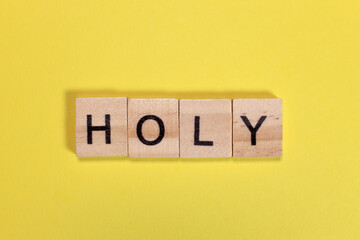 Holy word from wooden letters on yellow background