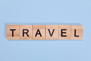 Travel word from wooden letters on blue background
