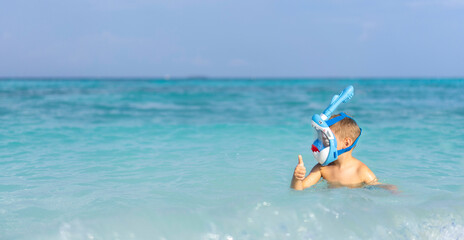 A little boy in a full face mask is snorkeling in the Maldives
