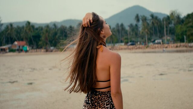 Beautiful long-haired girl twirling on the beach at sunset