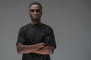 Studio shot of black man with dressed in t shirt posing with crossed arms.