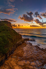 Fototapeta na wymiar Sunrise and clouds over the ocean and rock platform