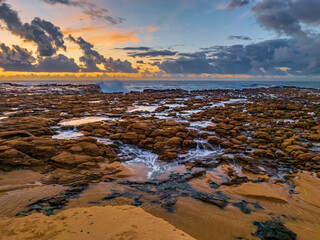 Sunrise and clouds over the ocean and rock platform