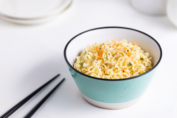 A Turquoise Bowl Filled with Instant Noodles on White and Bright Background 