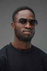 Fototapeta premium Shot of trendy black guy dressed in t shirt and sunglasses looking at camera.