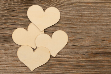 four bright wooden hearts on rustic brown wooden background with free space for text