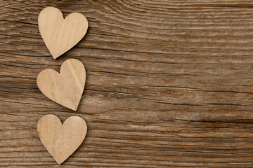 Obraz premium three bright wooden hearts on rustic brown wooden background with free space for text