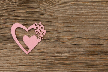 rose-colored playful heart on rustic brown wooden background with free space for text