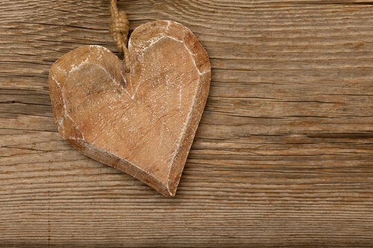 a wooden heart on rustic brown wooden background with free space for text