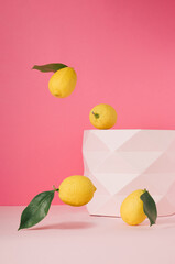 Lemons with green leaves against a pastel pink background. The design features a vertical frame.