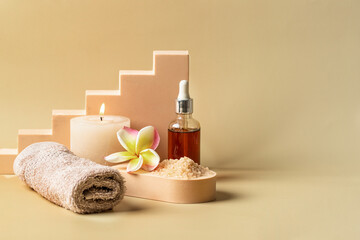 Auyrveda SPA still life. Exotic flower , oil bottle, sea salt, towel and candles on the podium at beige background. Copy space