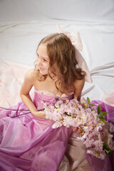 Portrait of cute kid girl posing in pink beautiful dress on a white background. Model in studio looking as gentle magic princess from fairy taly having photo shoot on white background