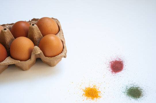 Directly Above The Photo Of Eggs In A Carton Box And Paint For Eggs On White Background.