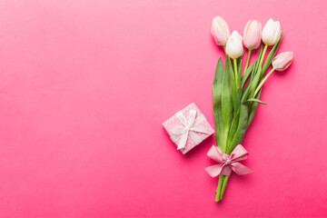 Pink tulips flowers and gift or present box on colored table background. Mothers Day, Birthday, Womens Day, celebration concept. Space for text top view