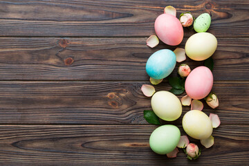 Happy Easter. Easter eggs on colored table with yellow roses. Natural dyed colorful eggs background top view with copy space
