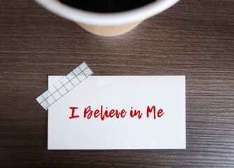 Coffee cup with note sticking on wood table written I BELIEVE IN ME, concept of positive self talk...