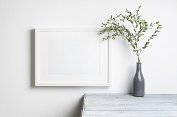 Blank landscape frame mockup with dry eucalyptus twig decor on wooden table