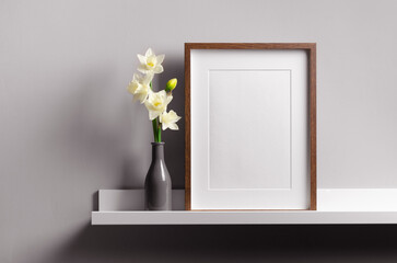 Wooden frame mockup on shelf with daffodils flowers, blank frame mockup