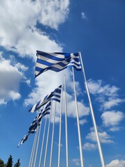 Vertical shot of flags of Greece waving under the wind