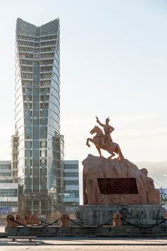 Das Reiterstandbild von Sukhbaatar, eines Nationalhelden der Mongolei zeigt mit der Hand auf die Fassade eines modernen Hochhauses auf dem Sukhbaatar-Platz in Ulan-Bator, der Hauptstadt der Mongolei