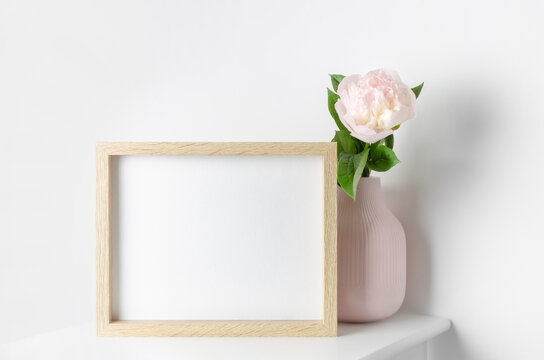 Wooden landscape frame mockup on white wall with peony flowers, blank mockup