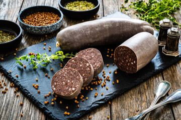 Raw buckwheat pudding on black stone cutting board on wooden table
