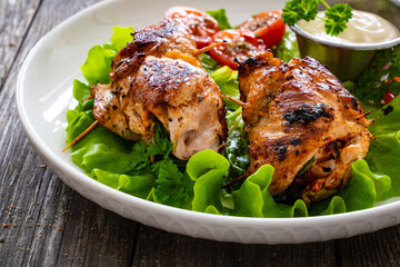 Wrapped chicken breasts filled with mozzarella cheese, spinach and tomato sauce served with green vegetables on wooden table
