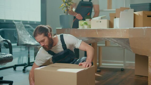 Employee Worker Sealing Cardboard Box Using Duct Tape Machine. Professional Packing and Unpacking Services. Packing and Preparation for Moving. Packing Supplies and Materials