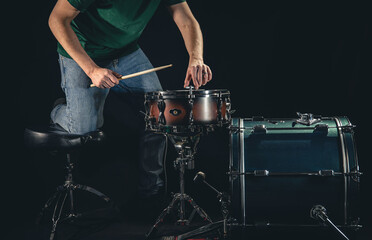 A man is a drummer and a drum set, the musician is preparing to play.