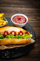 Hot dog, French fries and ketchup on wooden table
