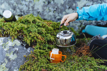 A person on a hike brews coffee, a tourist prepares breakfast in nature, a filter coffee bag to...