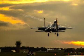 Fototapeta na wymiar Army fighter jet departing from the airport on the background of the calm yellow sunset