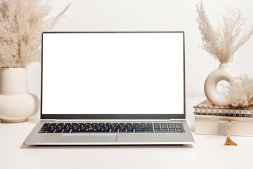 Mockup laptop with white screen on the table with vase, pampas grass, book and notepad. Aesthetic background for study, cozy home office, website promotion, social media