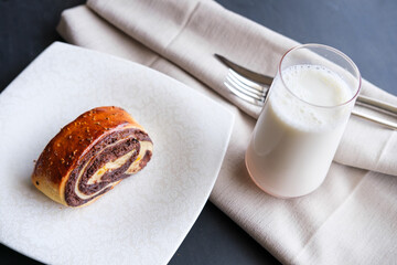Muffin slice with chocolate on white plate with milk. Beautiful photo of brown muffin and milk with fork and knife. Selective focus on muffin and top of the milk glass.
