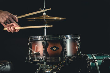 A man plays the snare drum against a dark background.