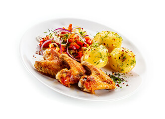Barbecued chicken wings with boiled potatoes and tomato salad on white background