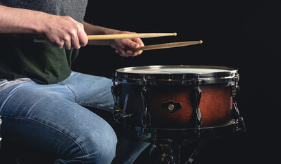 A man plays the snare drum against a dark background.