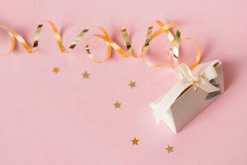 Festive pink background with a gift and golden gift ribbon. Happy mother's day, women's day or birthday in pastel colors. Mockup. Copy space