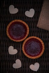 High-angle shot of two small cakes with red jam on them with white letters and hearts.