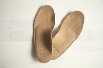 orthopedic insoles for shoes brown, made of natural materials, lies on a light surface of the table. Prevention and treatment of flat feet, shoe accessories