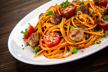 Spaghetti with meatballs in tomato sauce on wooden table
