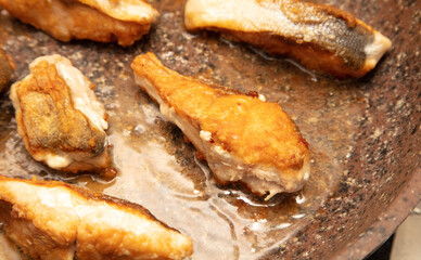 The fish is fried in a frying pan in oil. Close-up.