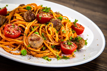 Spaghetti with meatballs in tomato sauce on wooden table

