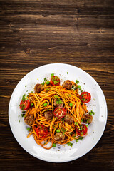 Spaghetti with meatballs in tomato sauce on wooden table
