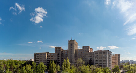 Fototapeta premium Spring aerial panoramic view on Karazin National University main building on blue sky. Located on Freedom (Svobody) Square with green park. Kharkiv city, Ukraine